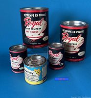 Photo of five cans of dry tempera powder poster paints against a blue background, showing Regal and Downey brands and various sizes.
