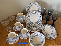 Full set of dinnerware and glassware displayed on table, showing pattern and quantity