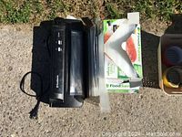 FoodSaver vacuum sealer machine with power cord, vacuum sealer bags laid next to device and boxes of FoodSaver bags.