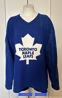 Front view of blue Toronto Maple Leafs Crosstar hockey jersey, size XL, with white maple leaf logo and text on front.