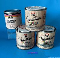 Photo showing four paint cans: three 250 ml Varathane Colours in Plastic enamel paint cans with Blue Smoke Satin #135 label and one 325 ml Tremclad Rust Paint green can.