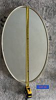 Oval 1950s wall mirror showing front reflective surface with measuring tape indicating length of about 28 inches
