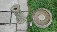 Top view of concrete bird bath pedestal and basin showing the size and shape of both pieces on pavement and grass background.