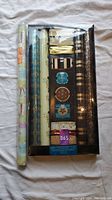 Multiple rolls of Christmas wrapping paper including one set in LCBO branded box with gold gift bows and themed designs