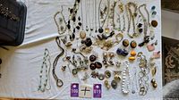 Full lot display of assorted jewelry laid out on white surface with various necklaces, bracelets, earrings, and pendants arranged.