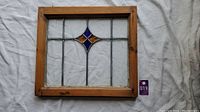 Front view of stained glass window showing wooden frame and colored glass diamond pattern.