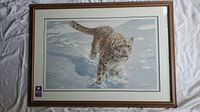 Overall view of the framed print showing the snow leopard in a snowy environment, with brown frame and white mat.