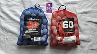 Photo of two mesh bags filled with white golf balls, one blue bag with 'Golf Nation 60 Value Bag' label and one red bag with 'Econo 60' label.