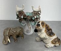 Three ceramic figurines: elephant, dog, and birds on floral centerpiece