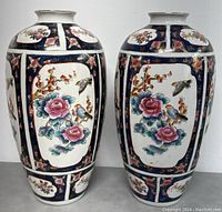 Front view of the pair of vintage Chinese 19-inch porcelain vases showing the floral and bird artwork with dark blue patterned borders.
