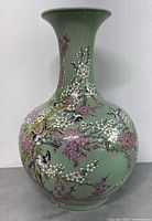 Front view of full vase showing celadon glaze, flared neck, painted blossoms and birds