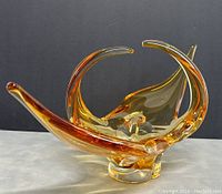 Side angle showing the sweeping amber glass curves and clear glass base