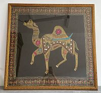 Framed embroidered camel artwork featuring detailed colorful stitching and ornate gold frame.