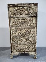 Front view of vintage dresser showing five carved drawers with bird and floral designs.
