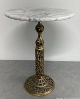 Front view of stand showing marble top and brass filigree pedestal.