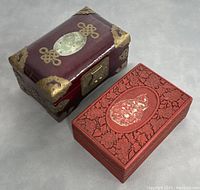 Two vintage Chinese jewelry boxes shown side by side on gray surface, highlighting differences in materials and design.