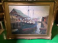 Close-up of the painted harbor scene featuring a boat and docks, with visible frame damage at corners.