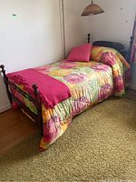 Wood single bed frame with floral multicolored bedding viewed from corner angle