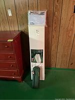 Photo of boxed twin size inflatable bed with pump and green mosquito net bag beside a wooden dresser