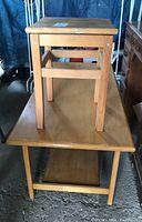 Wooden stool placed on top of a rectangular wooden coffee table with a lower shelf, showing general condition and relative size of both items.