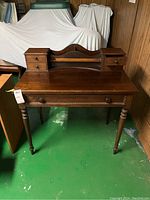 Full front view of vintage wooden desk showing desktop, raised back section with four small drawers, and one large drawer below.