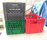 Three plastic milk crates stacked and side-by-side in garage area, one marked Borden.