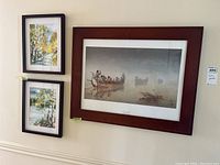 Overall view of three framed art pieces on wall: two smaller autumn birch tree watercolors and one large print of boat scene
