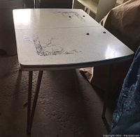 Top view showing the table surface with floral design and signs of wear.