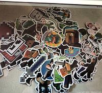 Pile of colorful Minecraft stickers featuring pixelated characters, swords, and game elements with white borders.