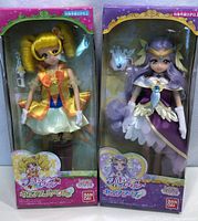 Two new Bandai anime character dolls in original window box packaging showing full front view of each doll and their accessories.