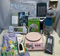Full lot of assorted kitchenware items including scale, bottle, utensils, placemat, towel