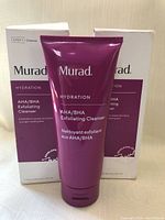 Front of two tubes of Murad Hydration AHA/BHA Exfoliating Cleanser in purple tubes with boxes, showing product name and branding.