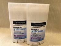 Front view of two white Neutrogena Mineral Ultra Sheer Dry-Touch Face & Body Sunscreen Sticks with SPF 50, 42g each.