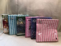 Six unopened packages of IHR paper napkins each with distinct floral or stripe designs.