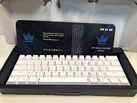 BIERYA DK61 SE mechanical keyboard with white keycaps inside damaged open box showing manual.