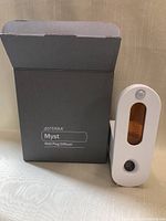 DoTerra Myst Wall Plug Diffuser box and diffuser unit shown side by side, box open at top.
