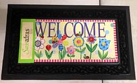 Front view of Sassafras welcome mat insert with colorful flower design, 'WELCOME' text, and green Sassafras label attached.