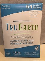 Photo of the front of the blue and beige box of TruEarth Eco-Strips laundry detergent showing branding, fresh linen scent, and 64 loads.