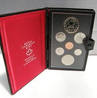 Opened black leather folding case showing red felt interior with 'Royal Canadian Mint' branding. Transparent plastic insert holds seven silver proof coins arranged in two rows.