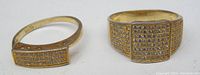 Photo showing both 925 silver rings side by side, gold-tone finish with rectangular textured faces featuring small clear stones