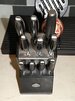 Front view of Hampton Forge kitchen knife block with knives inserted, showing logo on block and stainless steel knives with black handles.
