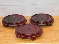 Three rosewood wooden circular display stands arranged on a wooden surface showing the overall look and color.