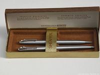 Sheaffer pen set featuring a silver-tone ballpoint pen and mechanical pencil in original box with branding and guarantee text.