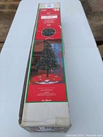 Box front showing brand, size, and picture of assembled tree with lights on, also mentioning stand included.