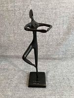 Front view of the black bronze ballet dancer sculpture on a neutral fabric background.