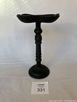 Side angled view showing the height and decorative top surface of the black cast iron garden stand