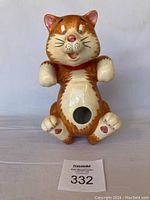 Front view of the ceramic cat bird feeder showing the facial expression, belly hole, and coloring.