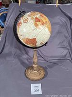 Photo of an 18-inch tall decorative globe with vintage map coloring, mounted on a wooden stand, showing a side view with visible land masses including Australia and part of Asia.