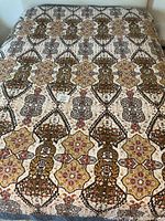 Full size quilt spread on a surface showing the overall patterned design with geometric and floral motifs in brown, yellow, red, and cream tones.