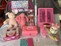 Full lot overview showing plush toys, Barbie items, backpack, umbrella, journal, and doll wardrobe cabinet